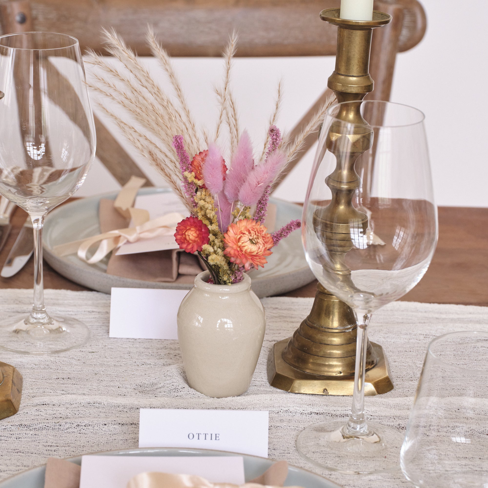 Elegant event or wedding table setting with wine glasses, vase of dried flowers, and bronze candle holder, wedding props and flowers from botanique workshop in london